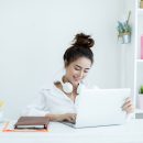 Beautiful young woman working on her laptop in her room.