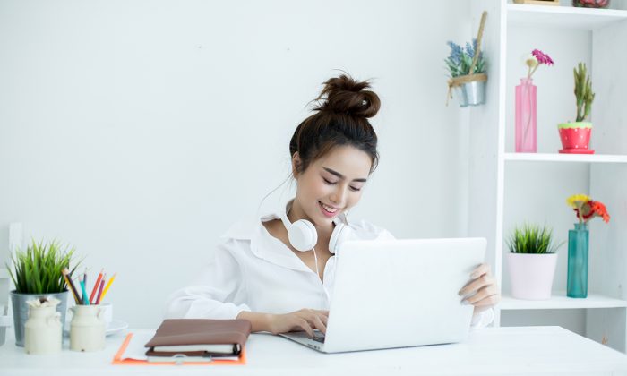 Beautiful young woman working on her laptop in her room.